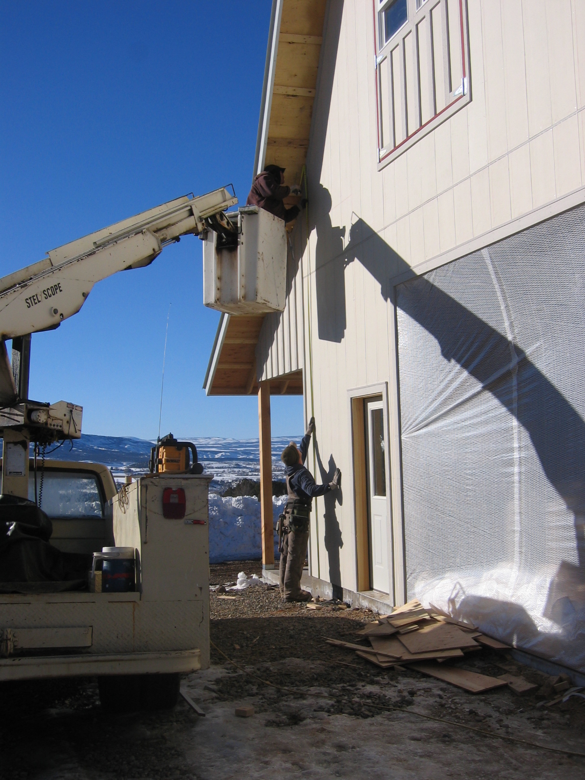 A man in a cherry picker is working on the last bits of the roof installation. 