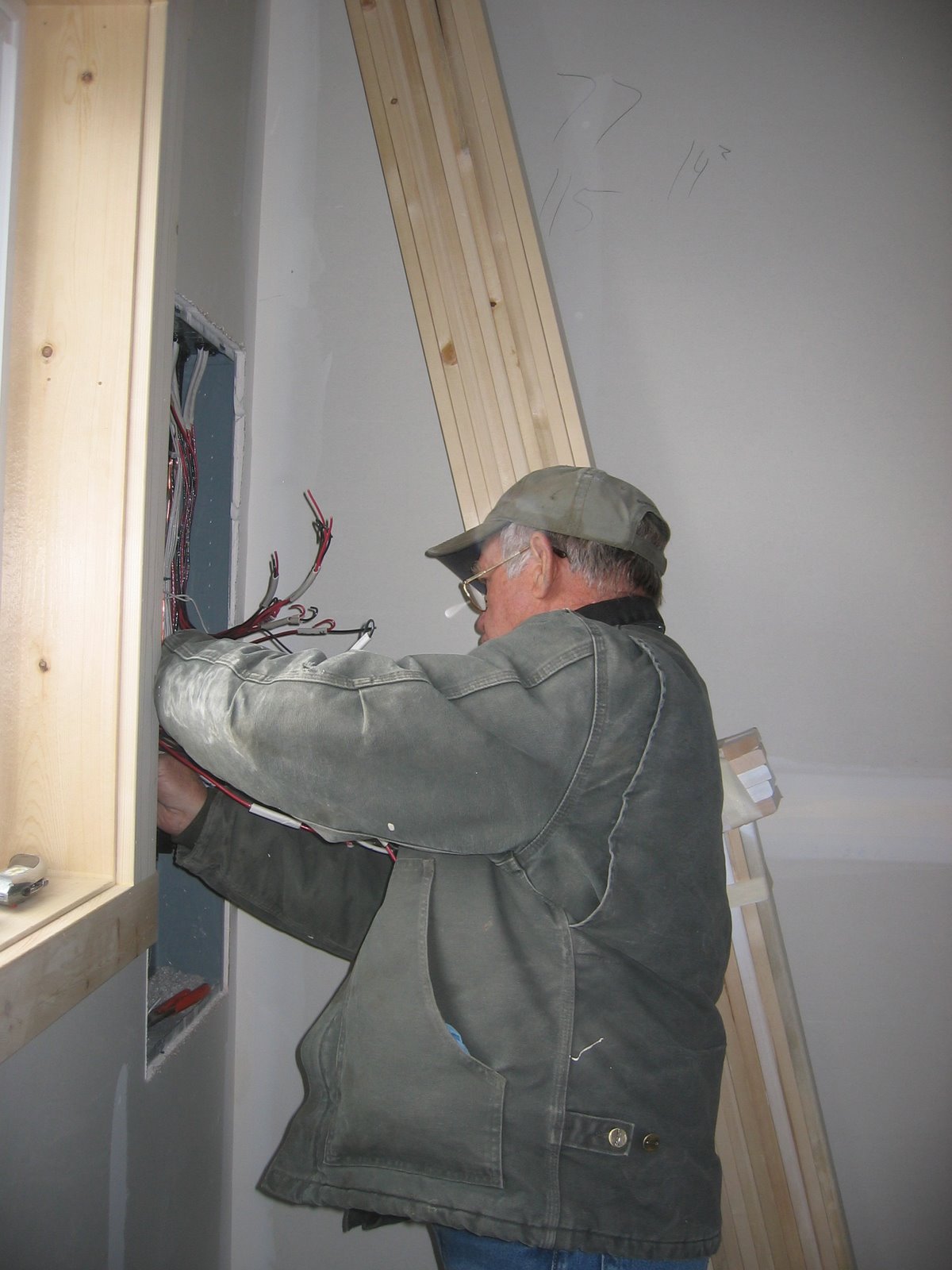 This man is working on the electrical panel in the shop. 
