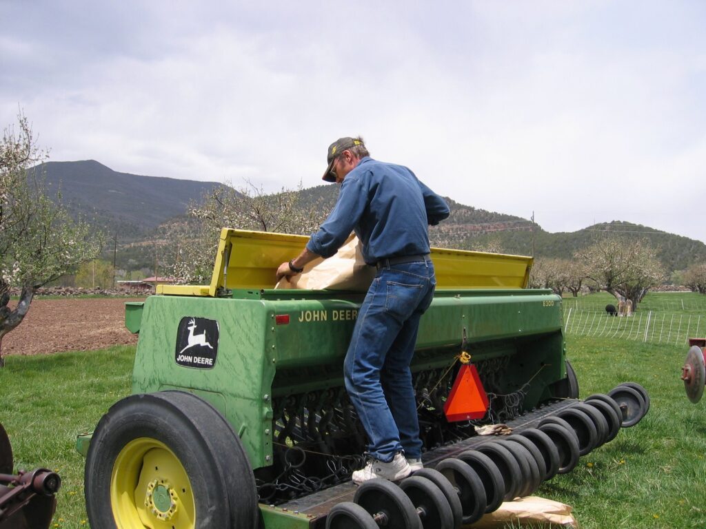 A farmer loads seed into a planter to reseed the field.