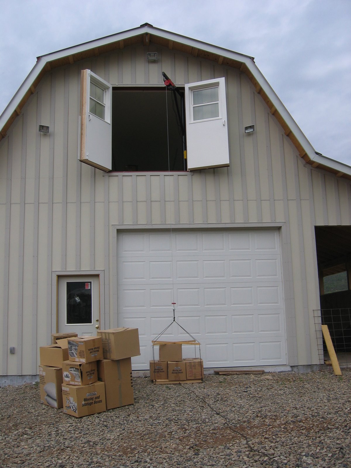 A crane located in the upper floor of the shop is being used to hoist boxes of wool.