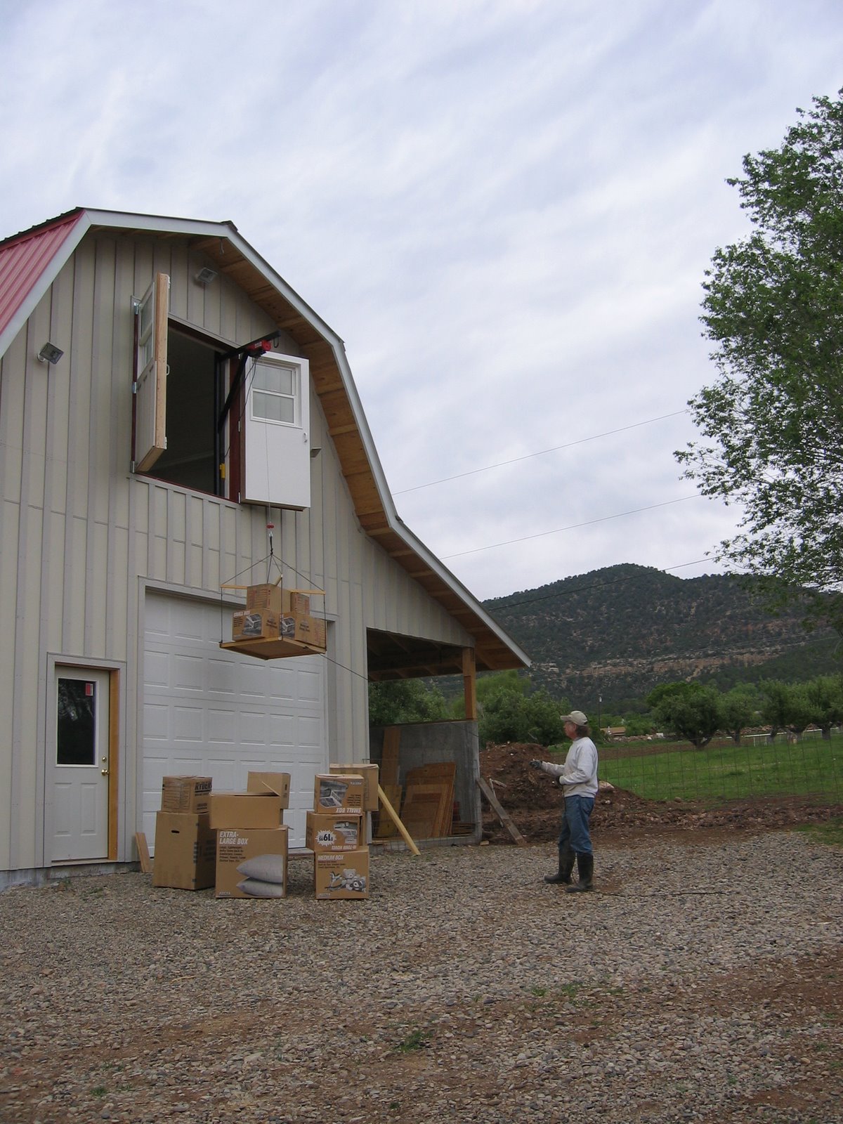 A crane located in the upper floor of the shop is being used to hoist boxes of wool.