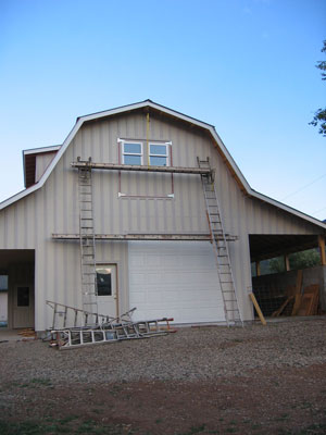 Scaffolding and ladders are set up alongside the shop for painting. 