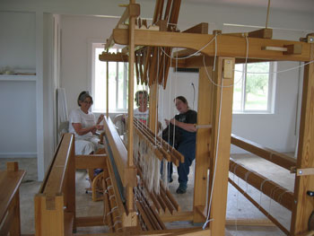 The girls are visible on the other side of the loom.