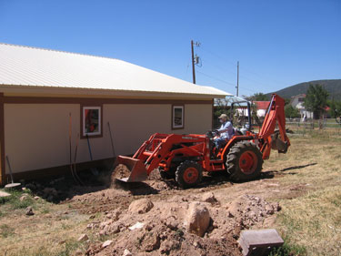 Ken is using the tractor to excavate an area for the heat sink pipe. 