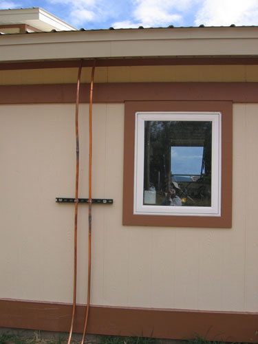 Some copper pipes or conduits are running from the roof down to the ground. 