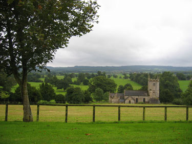 The Marston House is shown in a beautiful field of green grass and trees. 