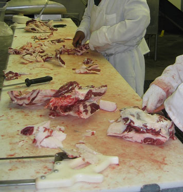 These workers are trimming fat from smaller sheep cuts.