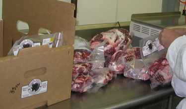 This worker is packing vacuum sealed meat into boxes.