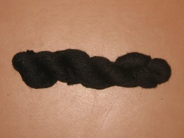 This is a black skein of woolen yarn, ready for sale. 