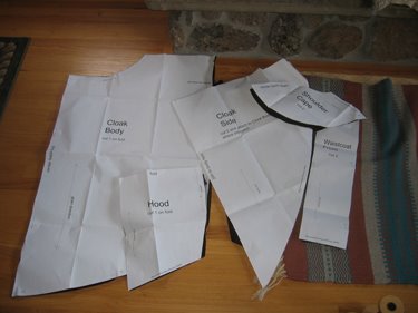 Several white pattern pieces for the cloak are laid out for viewing. 