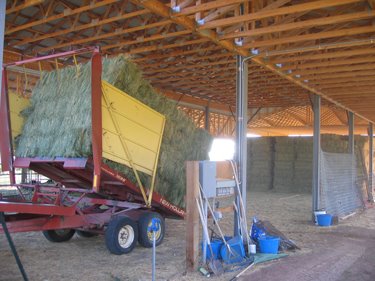 A haybale stacker is placing the bales in neat, stacked rows.