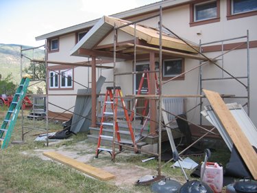 The old porch is surrounded by ladders and scaffolding in preparation for being torn down. 