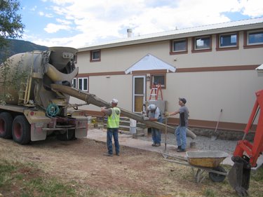 The men pour concrete footers for the new porch. 