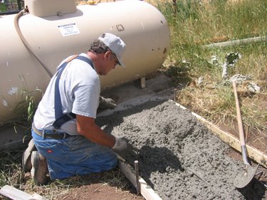 This man works on the concrete pad for the propane tank. 