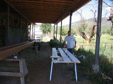 Here, a worker is in the process of priming and painting lumber. 