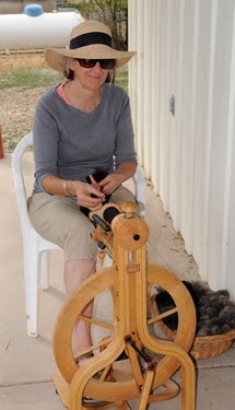 Margaret is spinning yarn by hand with the help of a spinning wheel.