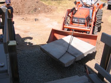 Bill uses the tractor to move a large slab of concrete into place. 