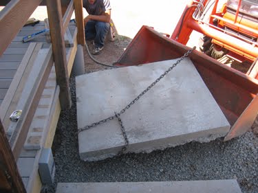 Bill uses the tractor to move a large slab of concrete into place. 