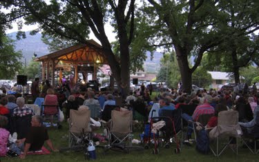 Tons of people sit in camp chairs throughout the park, listening to live music. 