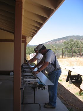 The crew bends and crimps the metal roof panels to fit together. 