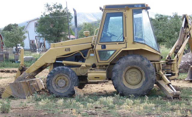 A large yellow backhoe digs a hole for the new solar panels. 
