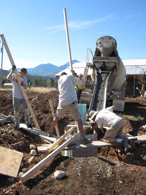 A crew of men pours concrete into a pier mold.