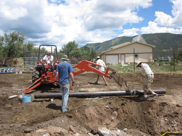 The crew uses the tractor to lift the pole into place.
