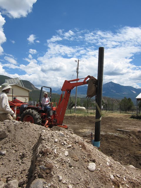 The crew uses the tractor to lift the pole into place.