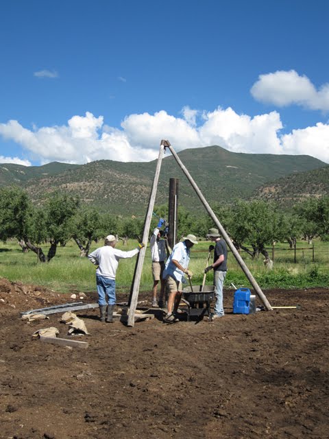 A group of men mixes mortar and adds brackets to the newly-erected poles.