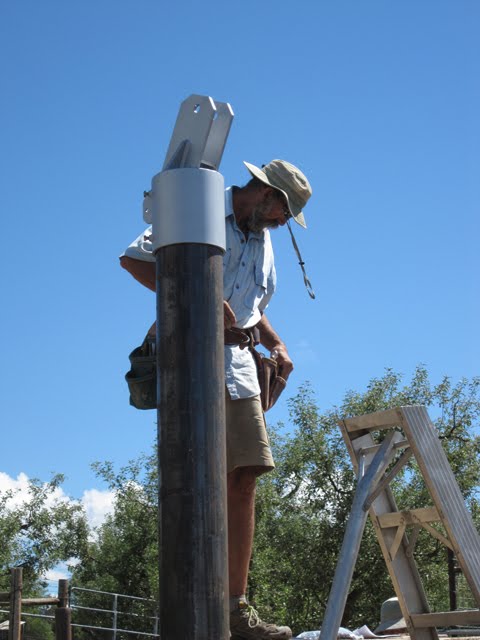 A man places the top bracket on one of the poles.
