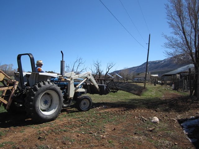 The tractor carries several welded fence panels with the brush rake.