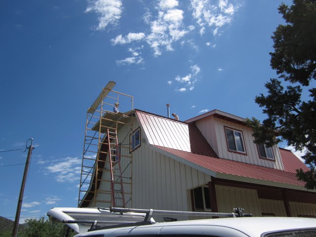 Tall scaffolding sits adjacent to a red-roofed barn.