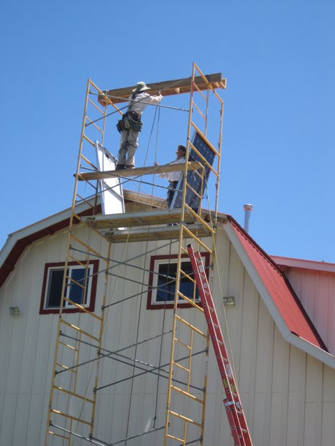 The men continue to raise solar panels using the pulley system. 