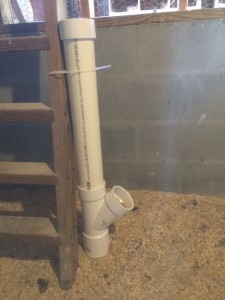 A PVC pipe feeder is zip-tied to a wooden post. 
