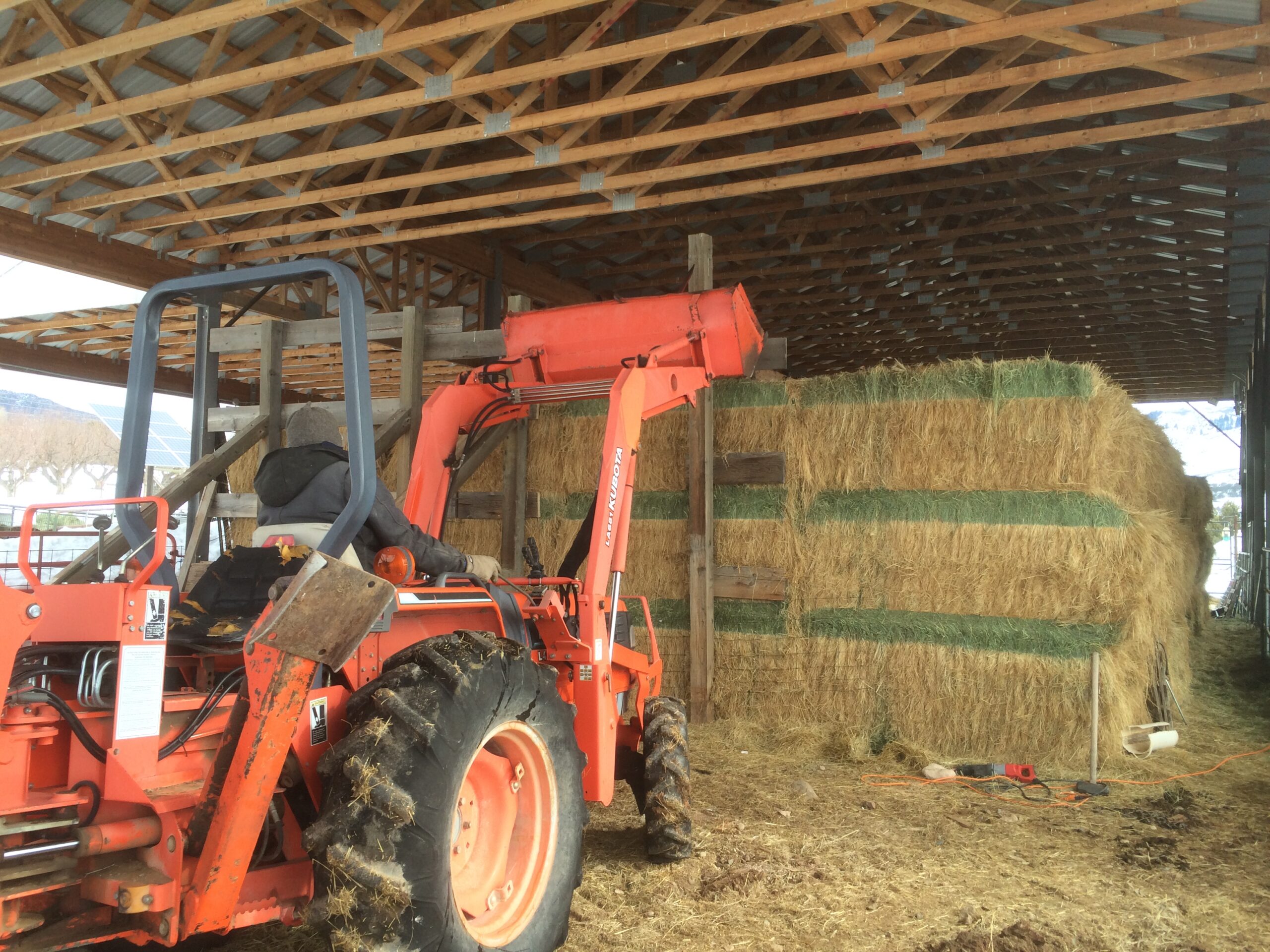 A person uses an orange tractor to remove wooden timbers.