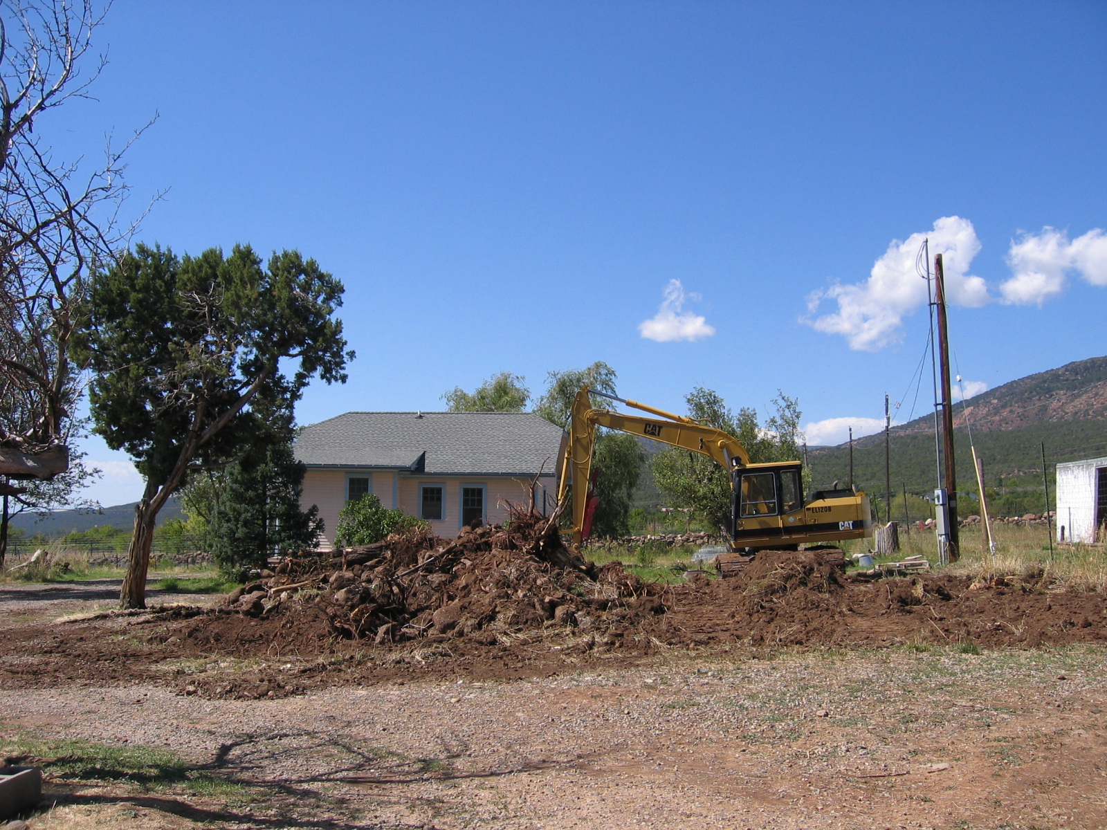 A backhoe operator screens rocks from good dirt.