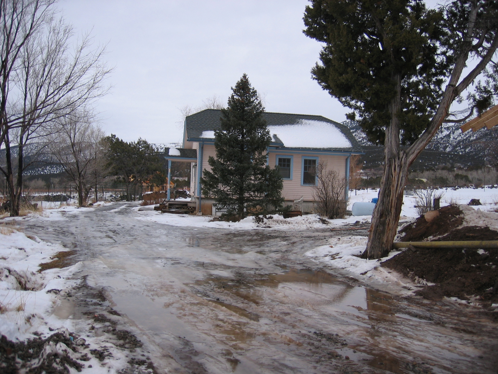 The driveway through the farm is covered in water, mud, and ice.