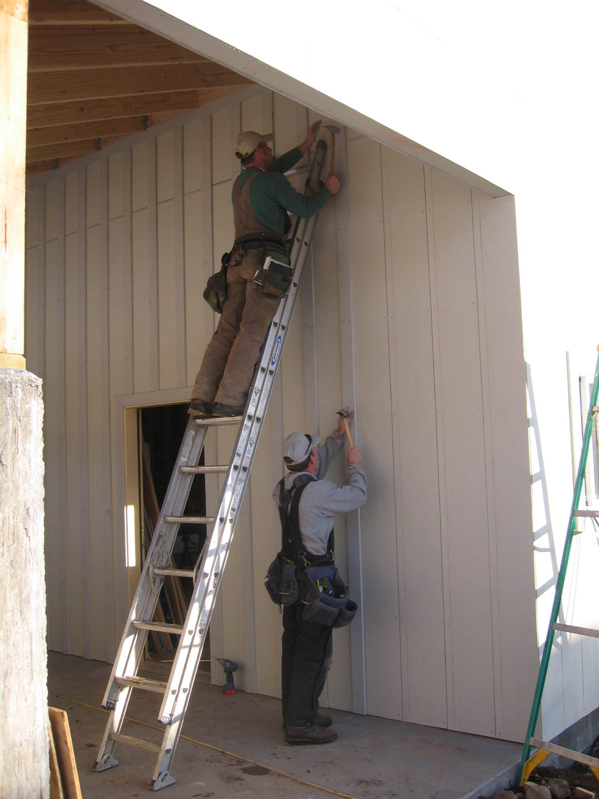 Construction workers are installing board and batten siding on the new shop.