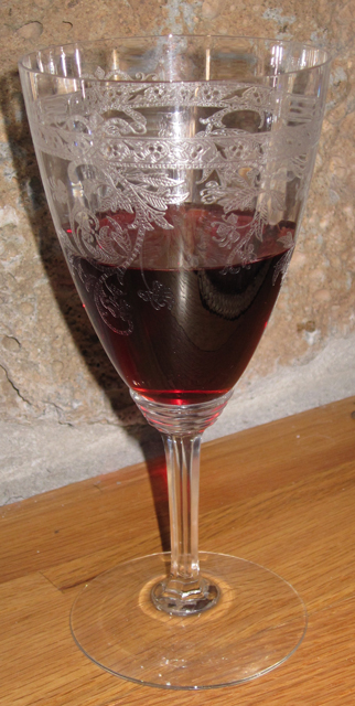 A beautiful etched wine glass sits near a rock fireplace wall.
