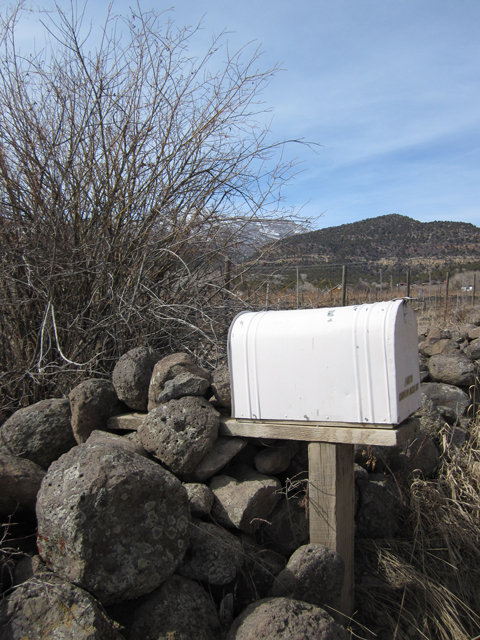A photo of a white mailbox bordered by piles of boulders. 
