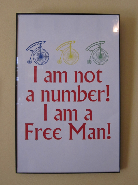 A photograph of an art piece on a wall which says, "I am not a number! I am a Free Man!"