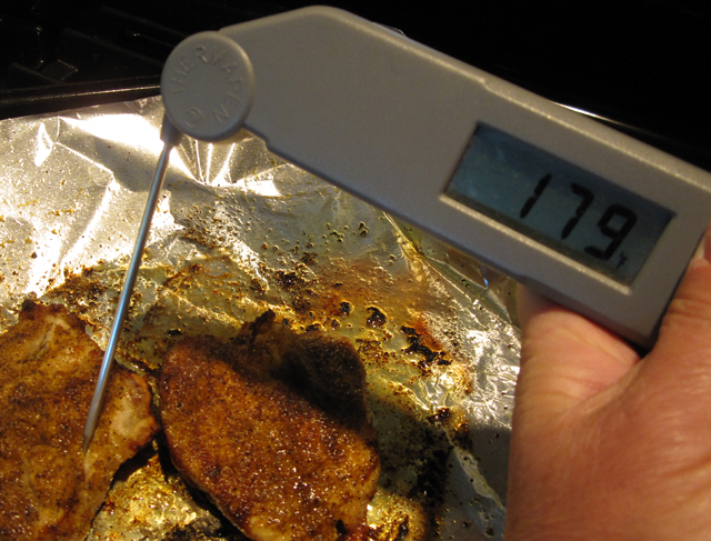 An instant-read thermometer checks the temperature of meat.