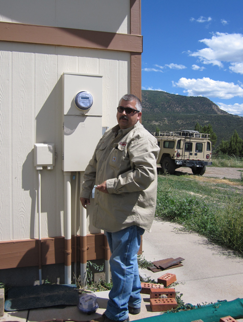 A man installs a new meter on the side of this house.