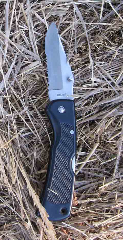 A pocket knife sits on a backdrop of hay.